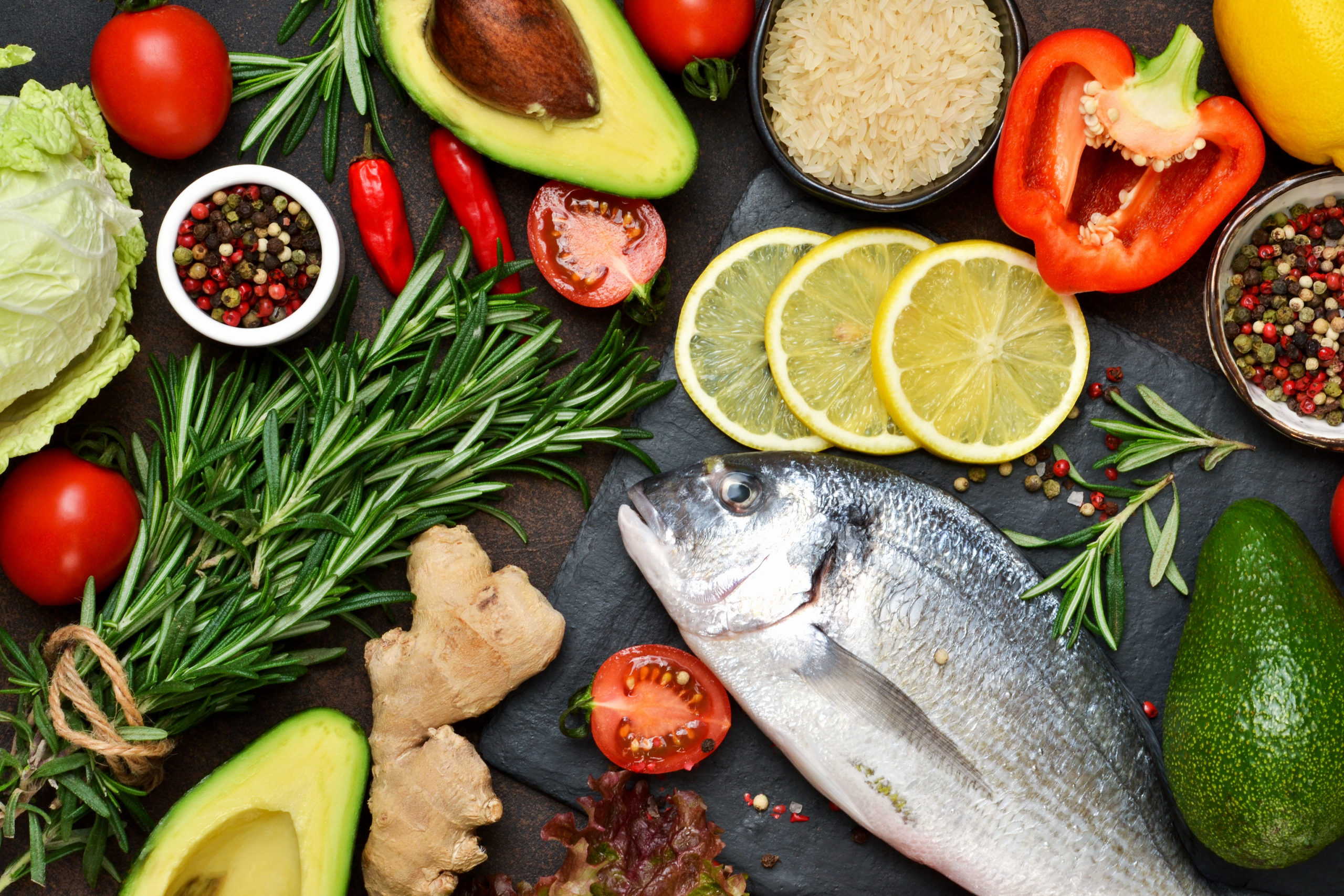Food background. Fresh, raw Dorado with a swallow, lemon, avocado on a dark concrete background.